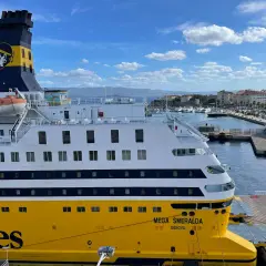 Le Mega Smeralda, un ferry de Corsica Ferries, est amarré dans un port pittoresque.