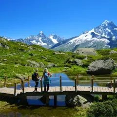 Deux randonneuses admirent le paysage spectaculaire lors d'une randonnée à Chamonix, avec des montagnes enneigées en arrière-plan.