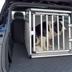 Un chien border collie attend patiemment dans une cage pour chien 90x60, installée dans le coffre d'une voiture.