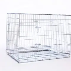 Une cage métal chien vide, prête à accueillir un compagnon. Elle est faite de barreaux argentés et possède un plateau amovible.