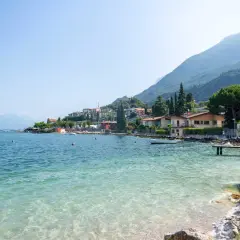 Vue paisible du lac de Garde, parfait pour la baignade. Des maisons colorées bordent la côte, adossées à des montagnes verdoyantes.