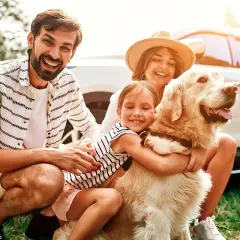 Une famille heureuse avec son chien, prête pour un week-end d'aventure. Idéal pour savoir où partir avec son chien en week-end.