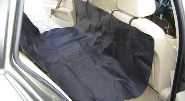 Protection siège voiture chien : une housse noire est installée sur les sièges arrière d'une voiture pour protéger l'intérieur des poils et salissures de votre compagnon.