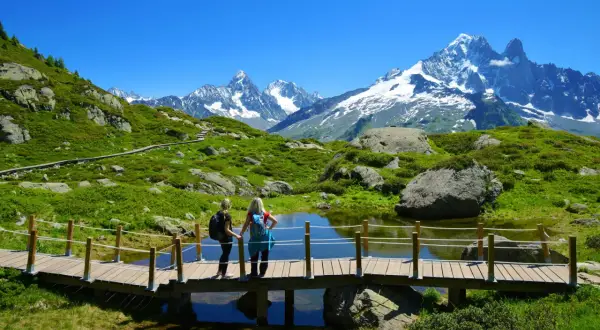 Deux randonneuses admirent le paysage spectaculaire lors d'une randonnée à Chamonix, avec des montagnes enneigées en arrière-plan.