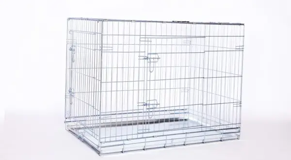 Une cage métal chien vide, prête à accueillir un compagnon. Elle est faite de barreaux argentés et possède un plateau amovible.