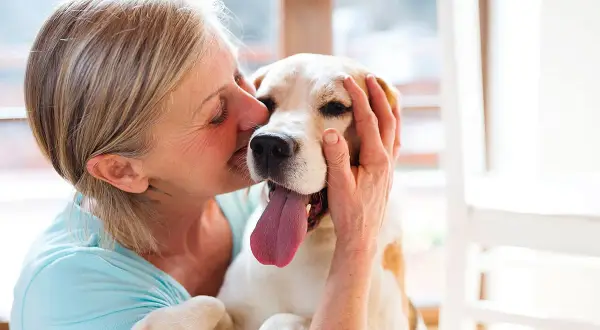 Une femme câline son chien, un moment de pur bonheur. Une véritable cure thermale avec chien pour le bien-être de tous.