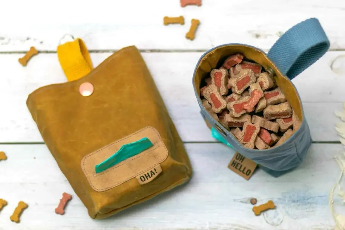 Deux sacs à friandises pour chien, un jaune moutarde avec distributeur de sacs, l'autre bleu rempli de biscuits. Idéal pour apprendre comment faire un sac ventral pour chien.
