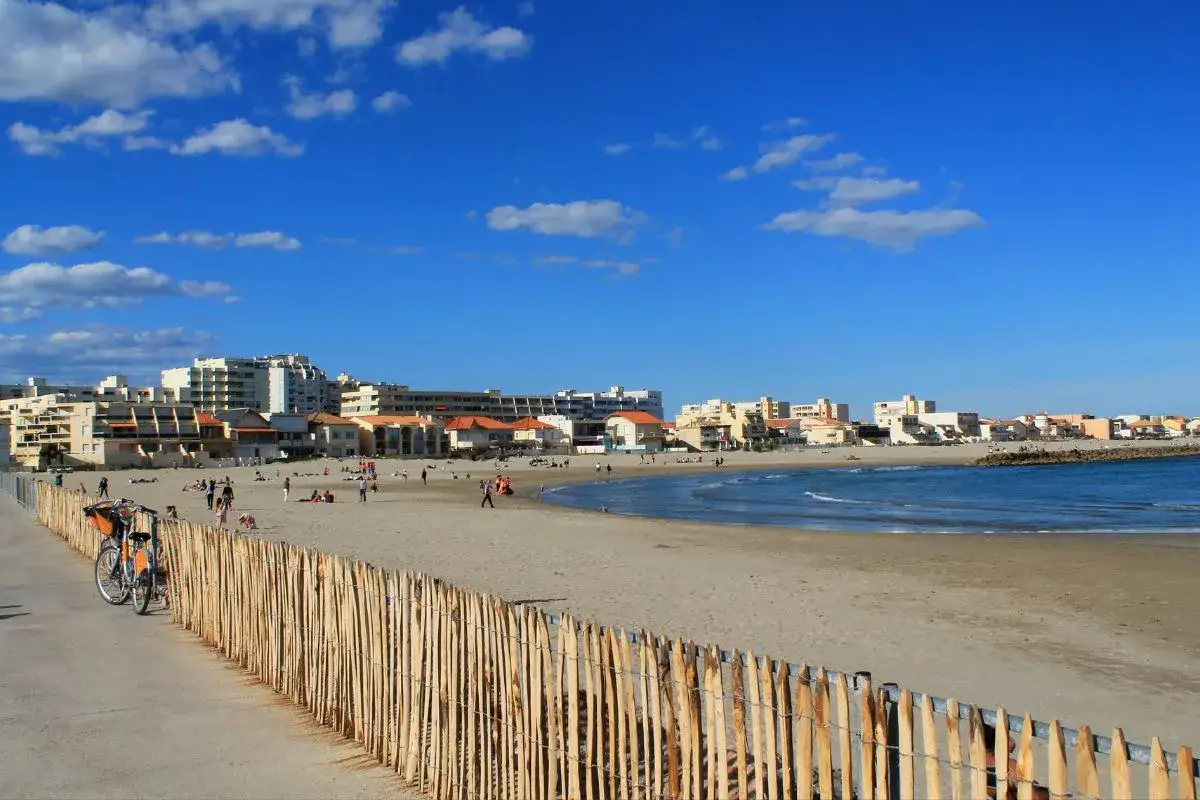 Plage au Grau-du-Roi, avec des vacanciers profitant du soleil. Les chiens sont autorisés sur cette plage, un endroit idéal pour des vacances en famille.