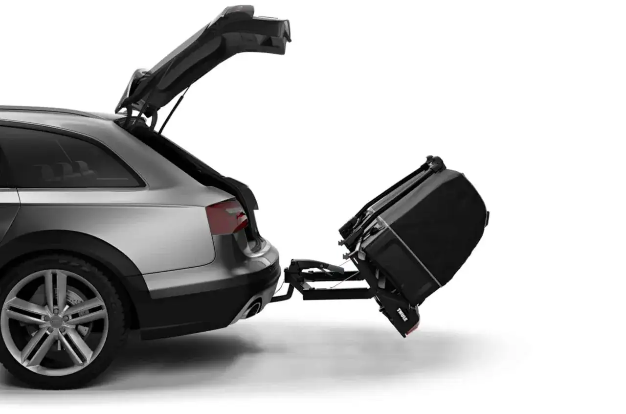 Un coffre sur attelage est fixé à l'arrière d'une voiture break, prêt à transporter des bagages supplémentaires pour un voyage.