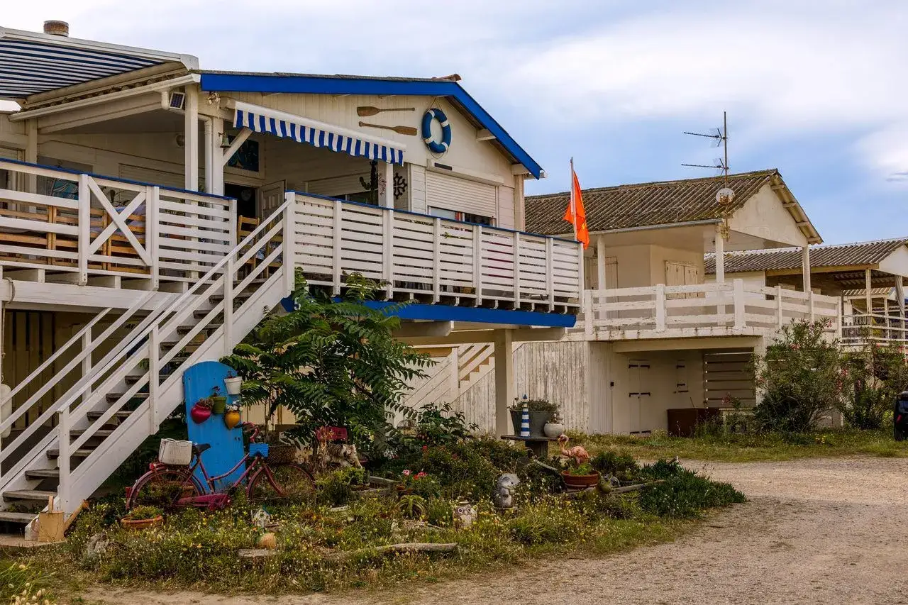 Cabanes de plage bleues et blanches sur la plage sauvage de Narbonne. Vélos décoratifs et jardin fleuri devant.