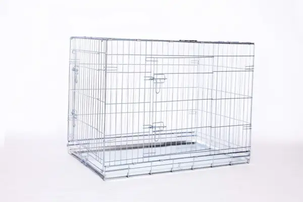 Une cage métal chien vide, prête à accueillir un compagnon. Elle est faite de barreaux argentés et possède un plateau amovible.