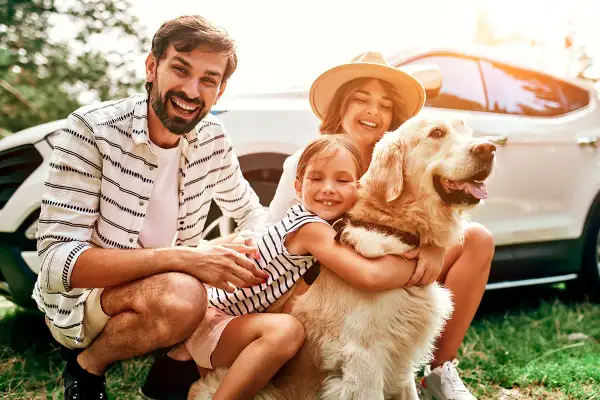 Une famille heureuse avec son chien, prête pour un week-end d'aventure. Idéal pour savoir où partir avec son chien en week-end.
